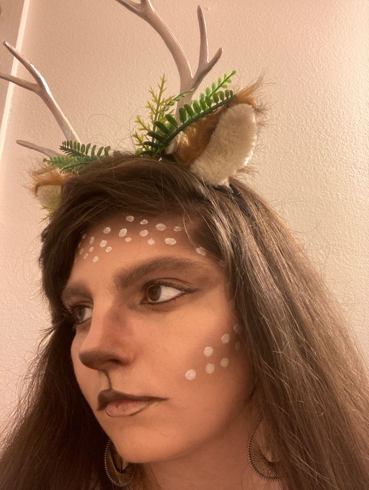 a woman with deer antlers on her head wearing white polka dots and green leaves