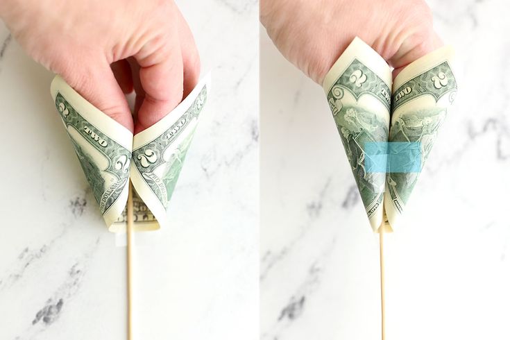 a person is holding money on top of a toothpick with a stick sticking out of it