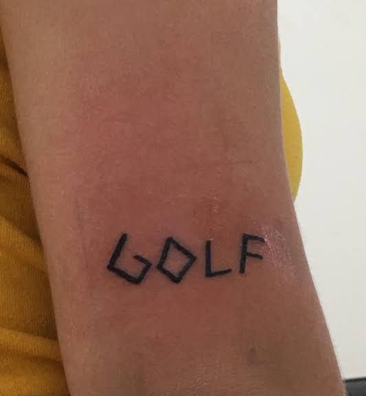 a person with a tattoo that says golf on their arm and the word golf written in black ink