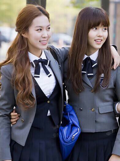 two girls in school uniforms standing next to each other with their arms around one another