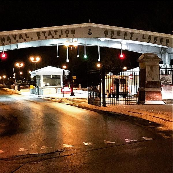 an entrance to the naval station and great lakes at night with traffic lights lit up