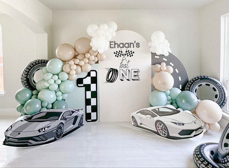 a room filled with balloons and cars on the floor next to a wall that reads 1