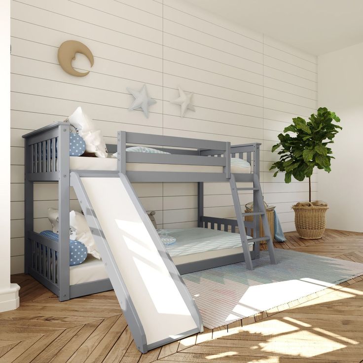 a bunk bed with a slide next to it in a room that has white walls and wood floors