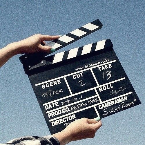 a person holding a clapper in front of a blue sky with writing on it