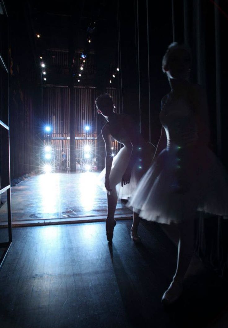 two ballerinas are dancing in the dark