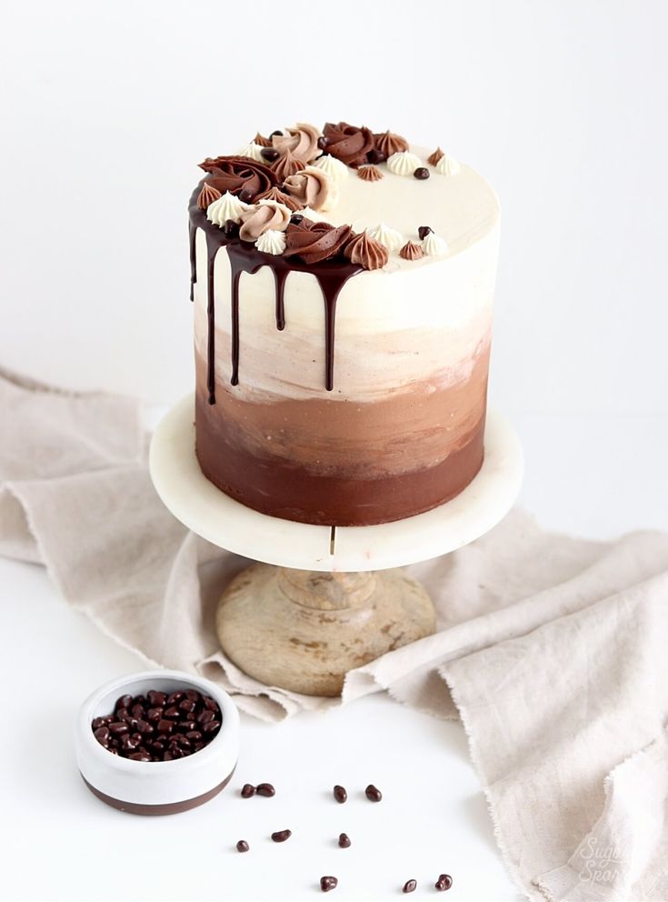 a cake with chocolate and white frosting sitting on top of a table next to coffee beans