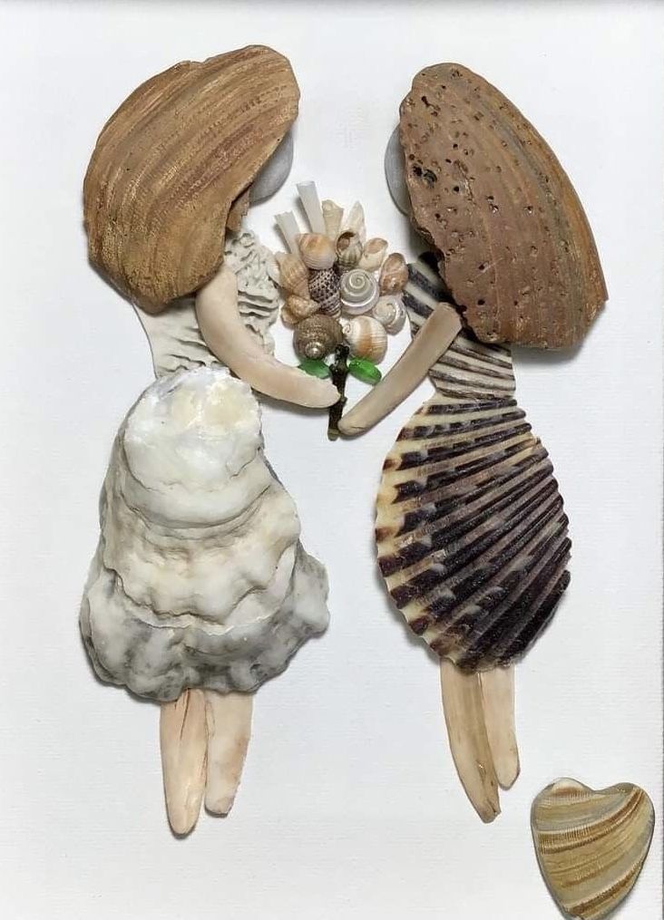 three seashells and shells are arranged on a white surface, with one shell in the shape of a woman's head