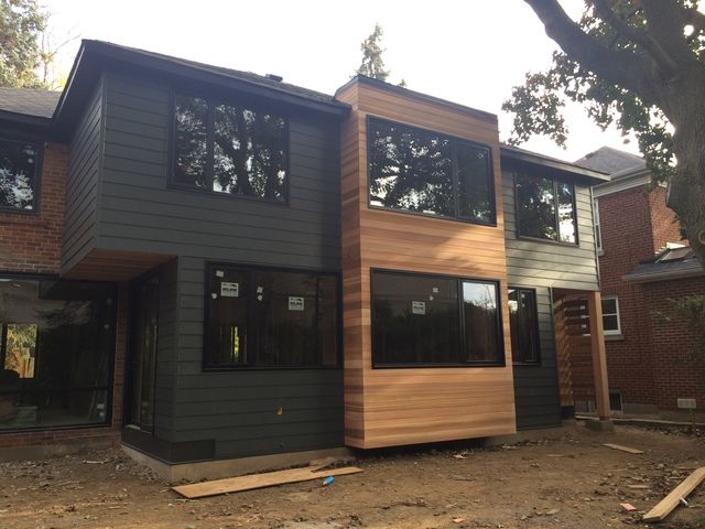 a house that is being built with wood siding on the outside and windows in the front