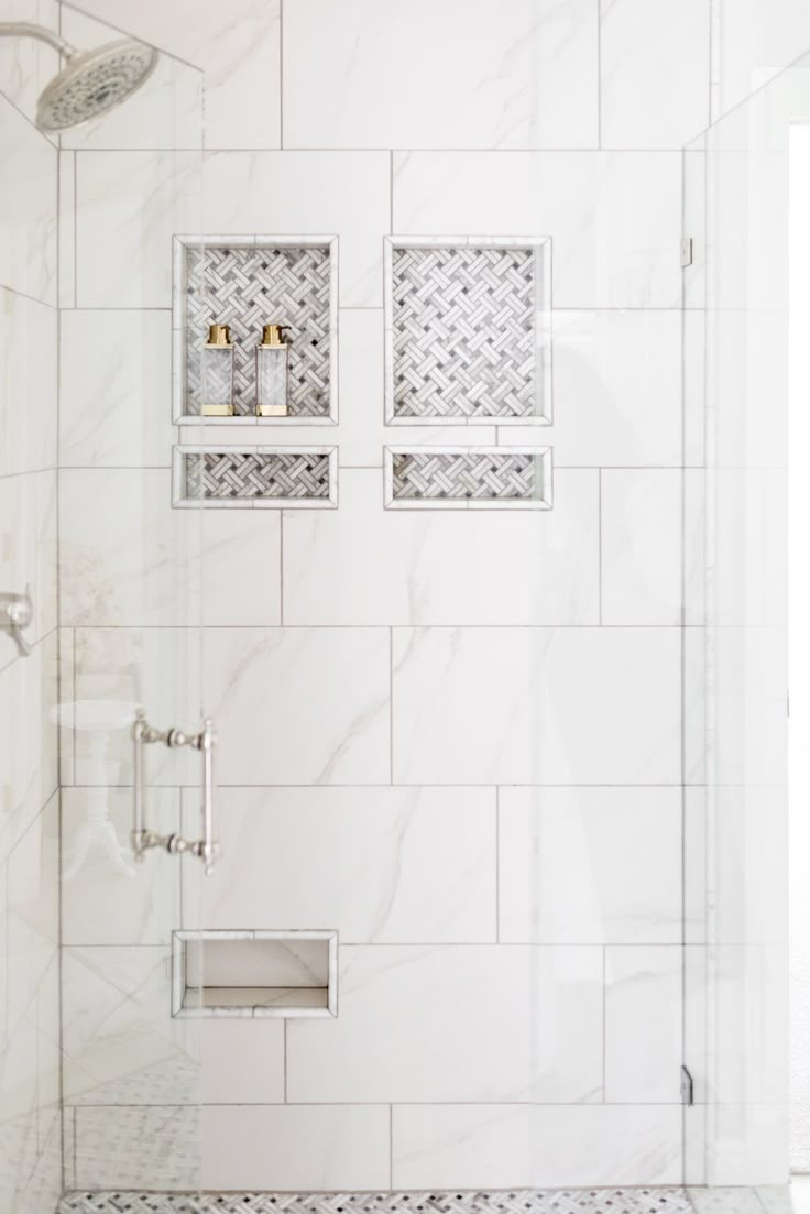 a white tiled shower with two shelves on the wall