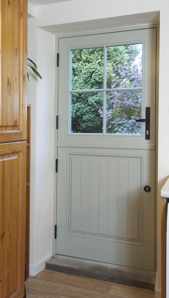 a white door with a glass window in the center and wood paneling on the side