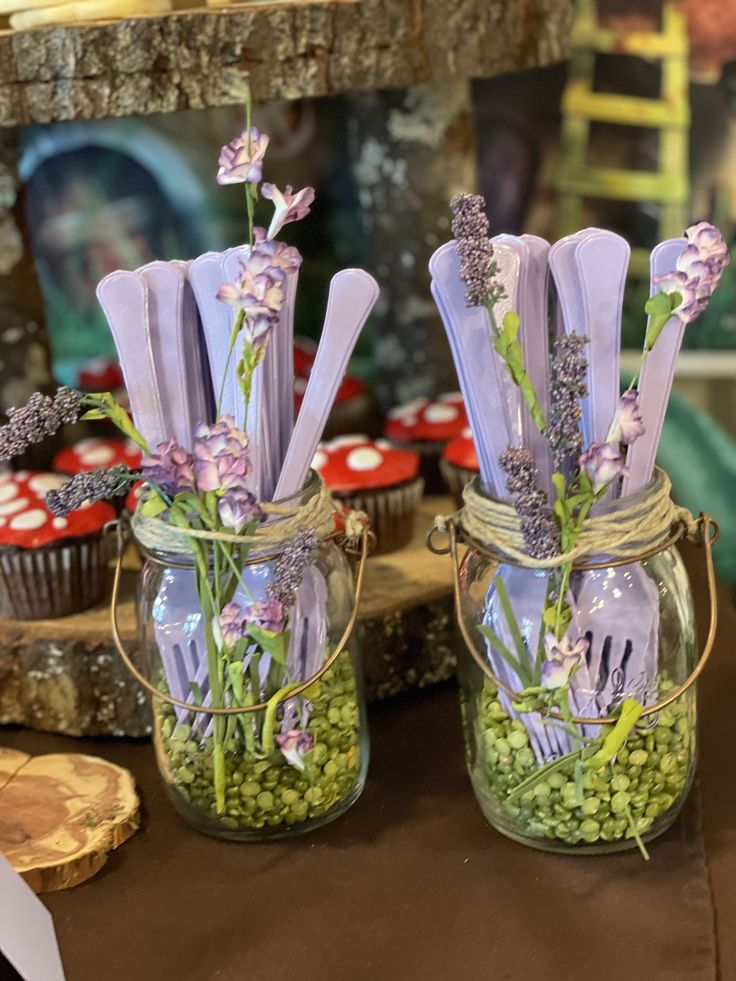 two jars filled with cupcakes and purple flowers