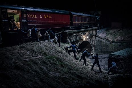 several people are walking up the side of a train track at night, with one person holding onto another man's hand