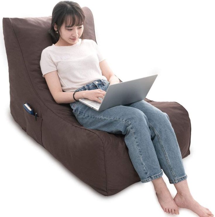 a woman sitting on a bean bag chair using a laptop