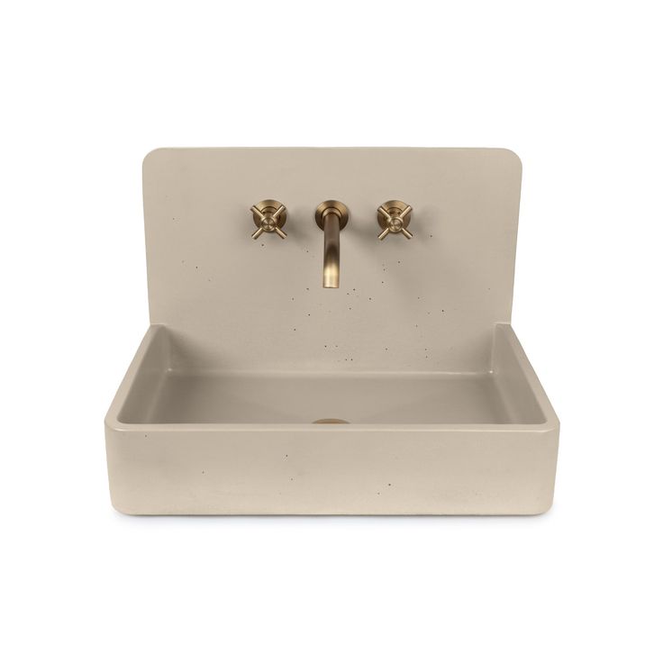 a white sink with two brass faucets on the front and side handles in gold