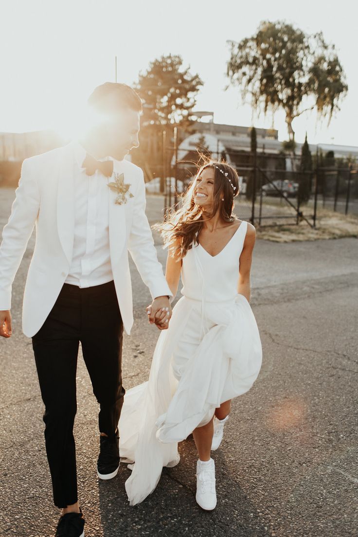 a man and woman holding hands while walking down the street in front of each other