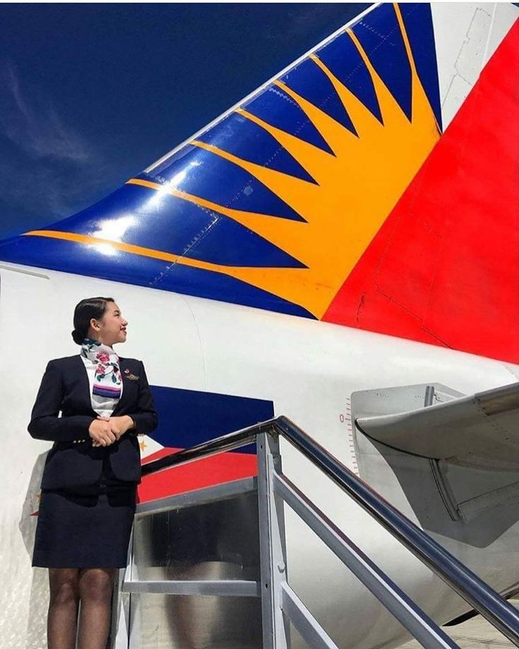 a woman is standing on the stairs next to an airplane