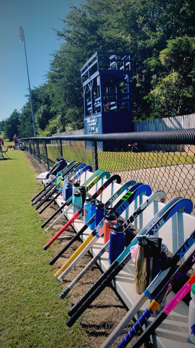 a row of baseball bats sitting on top of a grass field next to a fence