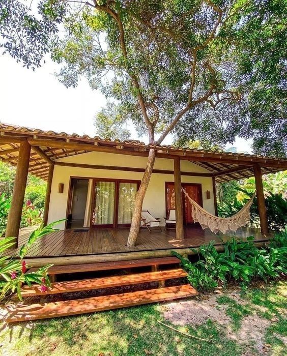 a house with a hammock on the front porch and trees in the back