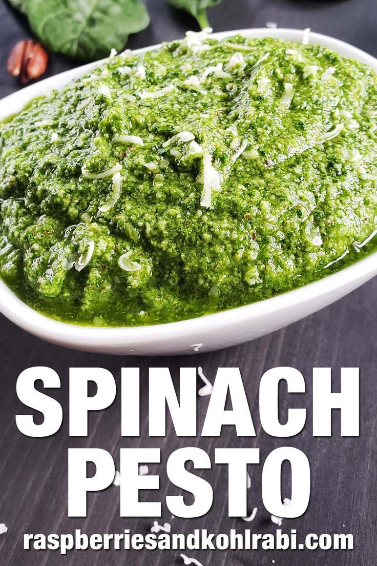 spinach pesto in a white serving dish with basil leaves and spices around it