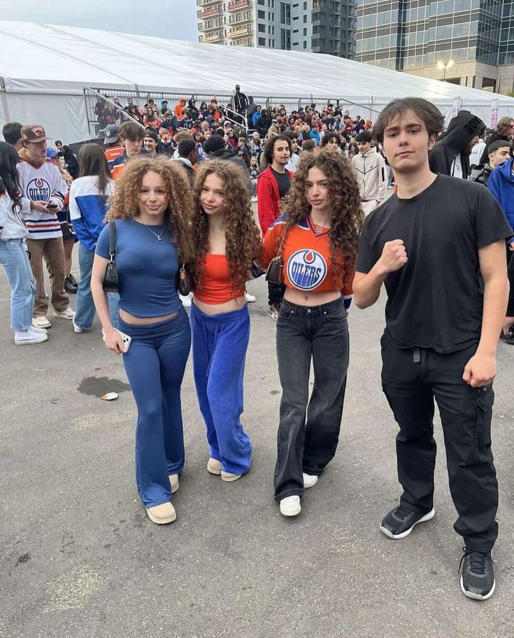 three young people standing next to each other in front of a large group of people