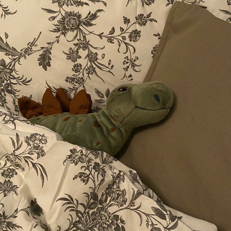 a stuffed animal laying on top of a bed next to pillows and pillowcases