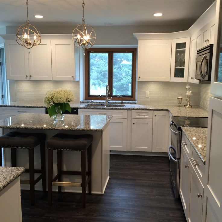 a kitchen with white cabinets and marble counter tops