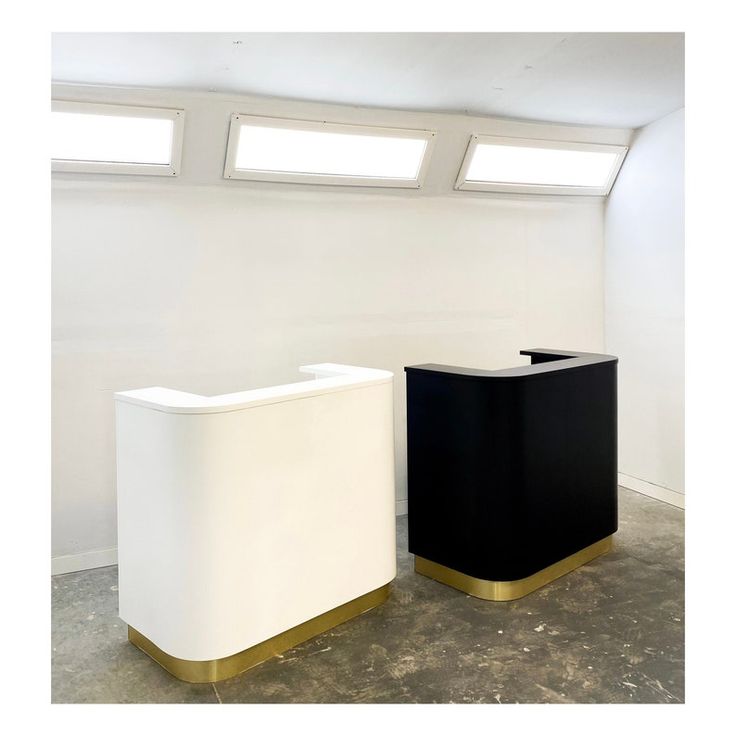 two black and white reception tables in an empty room with skylights above the windows