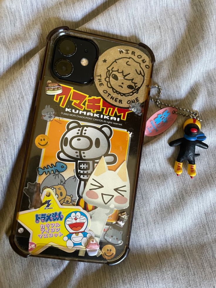 an iphone case with stickers and a keychain laying on top of it