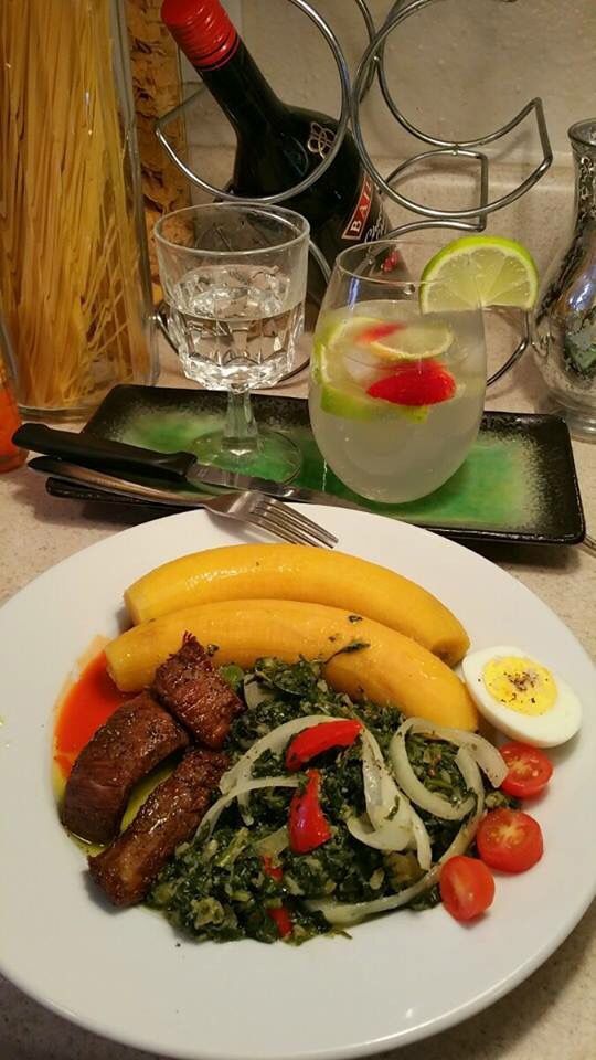 a white plate topped with meat and veggies next to a glass of wine