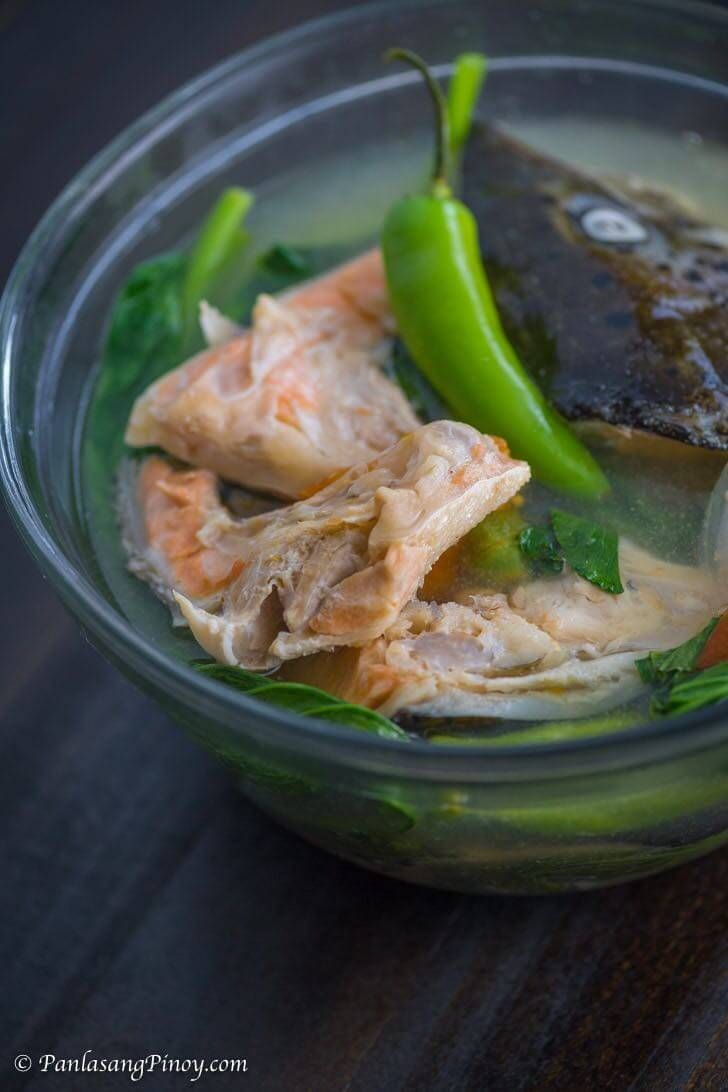 a bowl filled with fish and vegetables on top of a wooden table