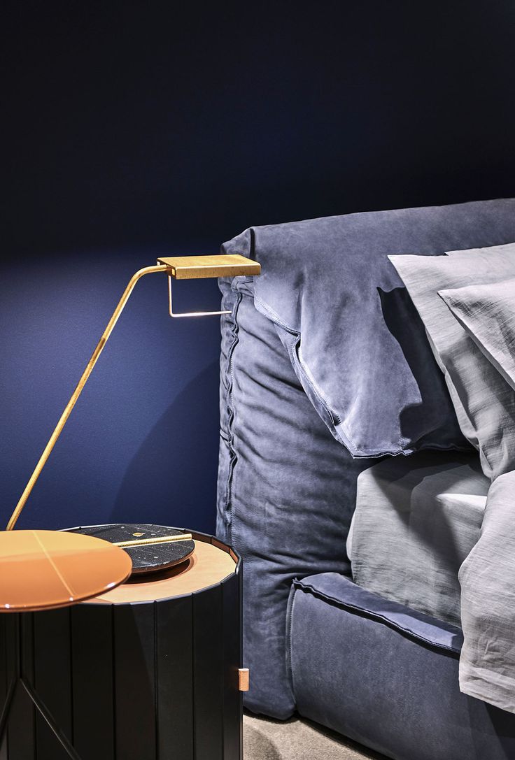 a bed with a blue comforter and a yellow lamp next to it on a night stand