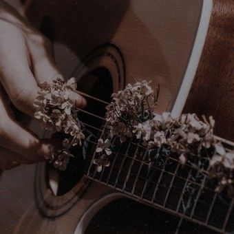 a person playing an acoustic guitar with flowers on the fret and in front of them