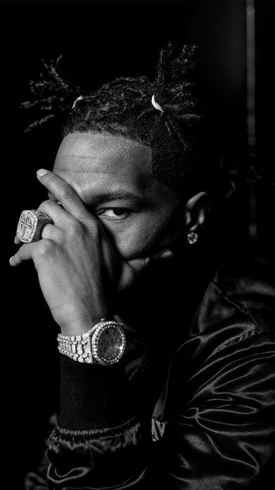 a black and white photo of a man with dreadlocks holding his hands to his face