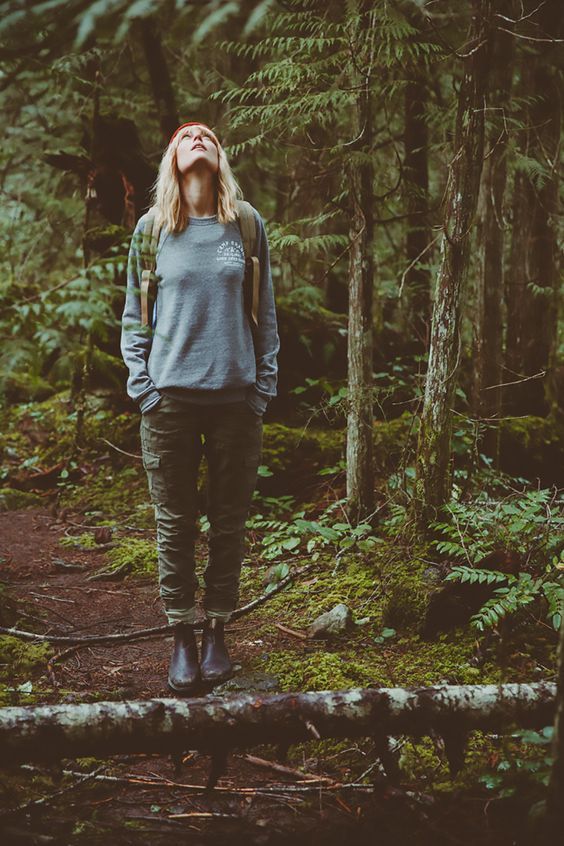 a woman standing in the middle of a forest with her eyes closed and looking up