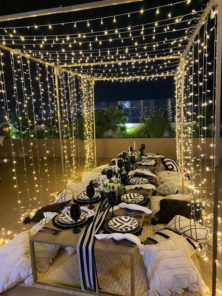 a table set up with black and white place settings for an outdoor dinner or party