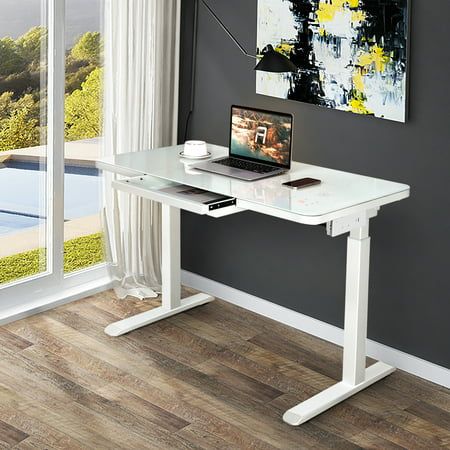 a laptop computer sitting on top of a white desk next to a large glass window