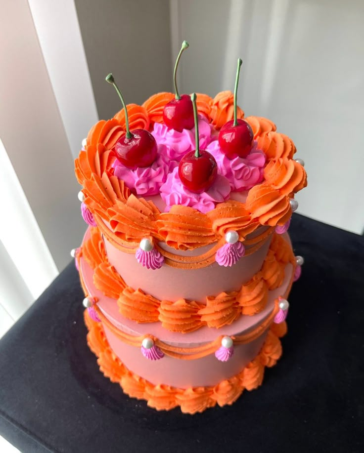 a three tiered cake with cherry toppings on top and decorations around the edges