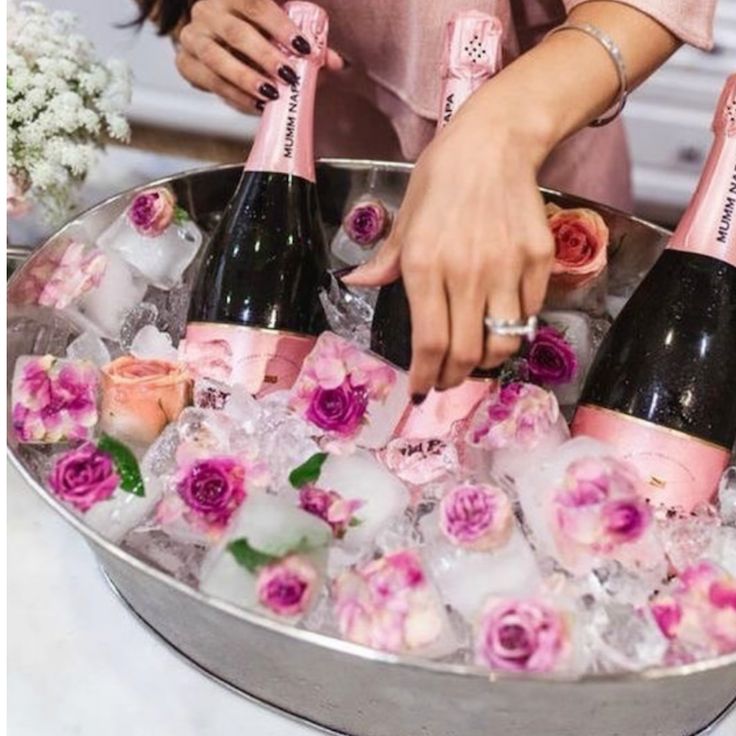 a woman is holding a bottle of champagne in an ice bucket with roses on it