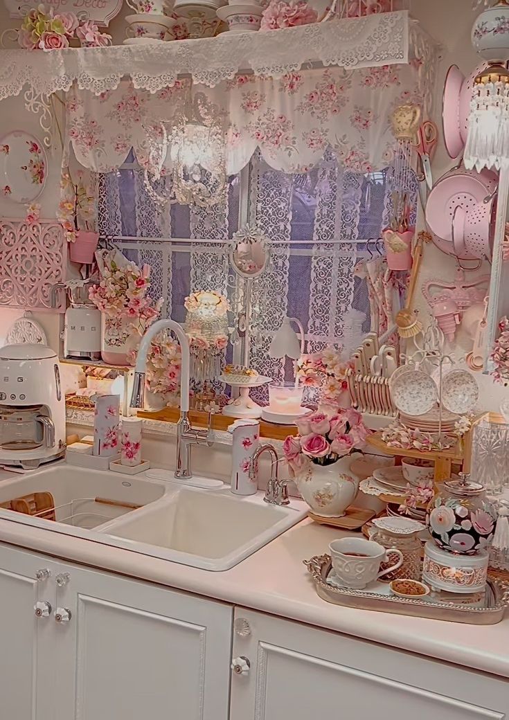 a kitchen filled with lots of pink and white decor on top of a counter next to a window