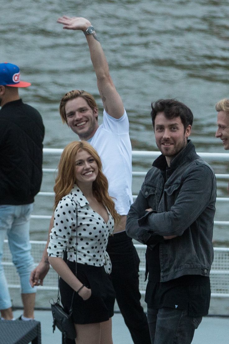 four people are posing for the camera with their arms in the air and one person is holding his hand up