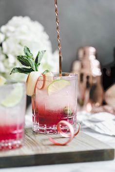 two glasses filled with drinks sitting on top of a wooden tray