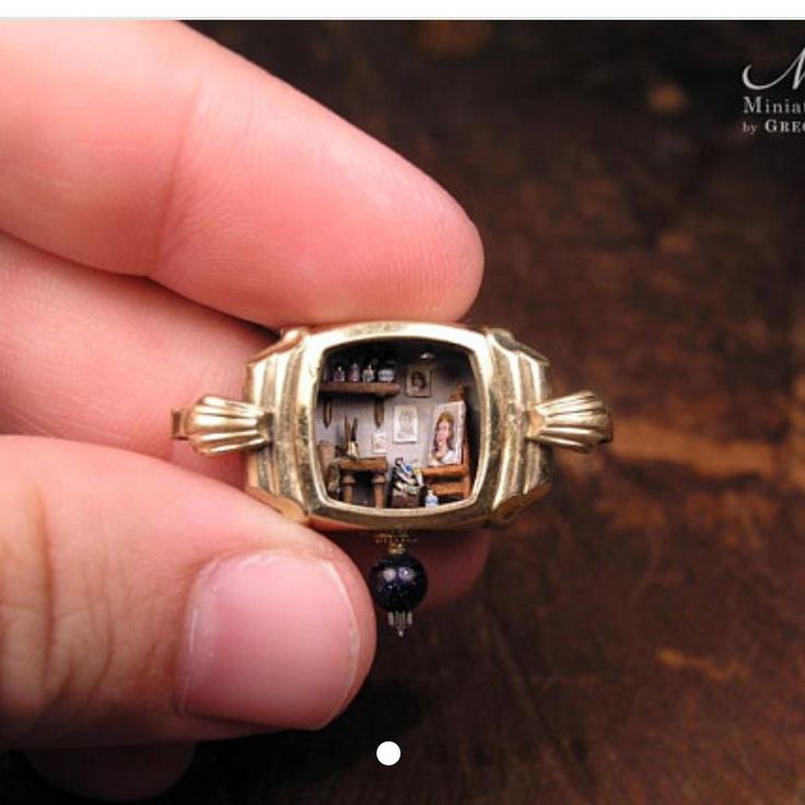 someone is holding a miniature ring with pictures on the front and back of it in their hand