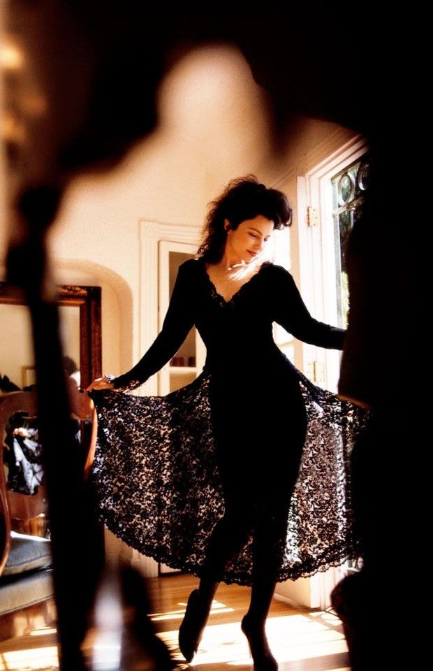 a woman in a black dress is walking through the room