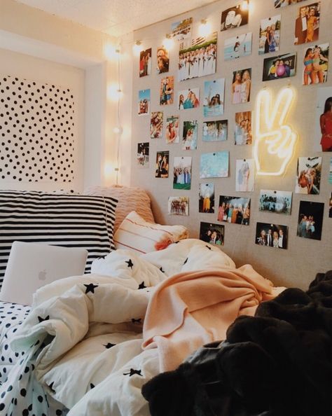 an unmade bed with many pictures on the wall and lights hanging above it in a bedroom