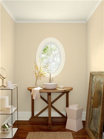 a bathroom with blue walls and wood flooring has a round window in the corner