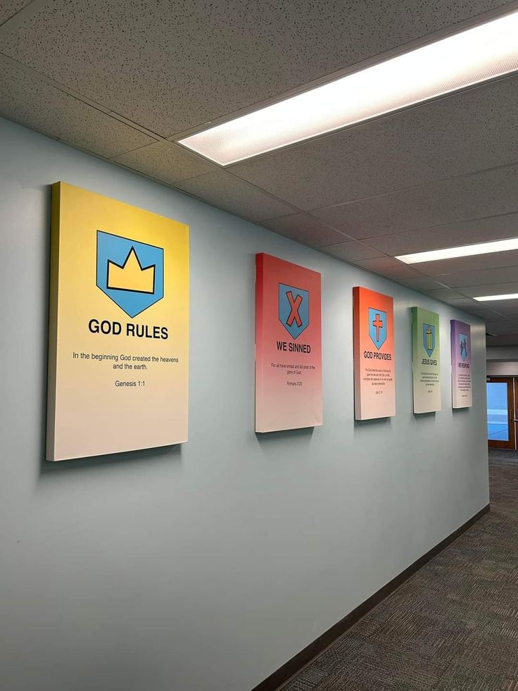 a wall with posters on it in an office building or conference room that says god rules