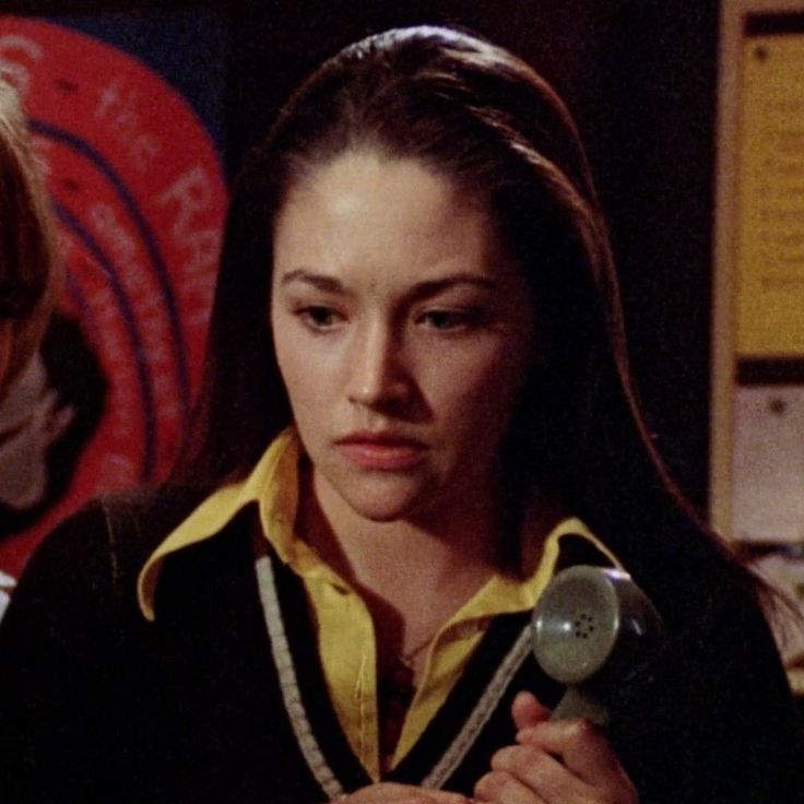 a woman holding a hair dryer in her hand and looking at the camera while standing next to another woman