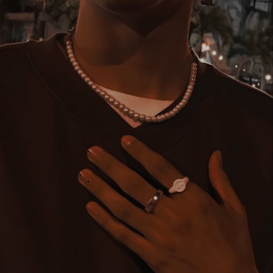 a close up of a person wearing a pearl necklace and pearls on her ring, with a cityscape in the background