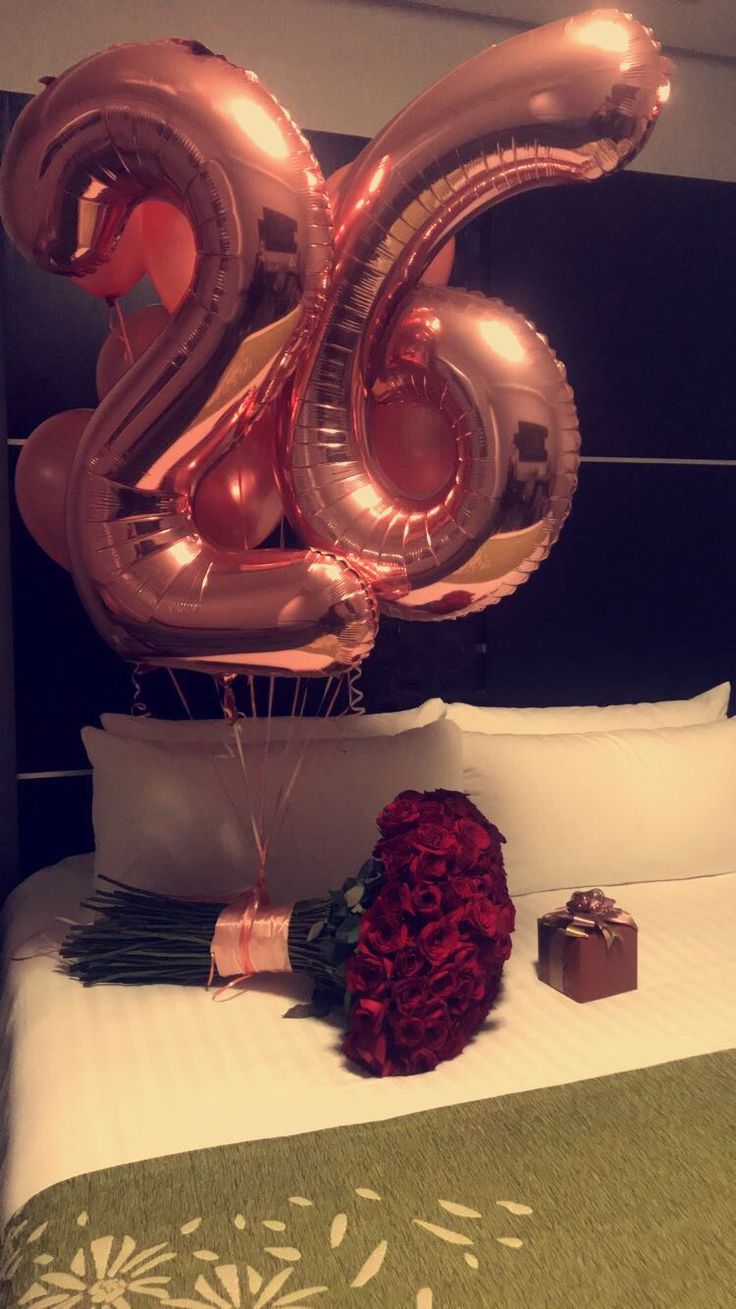 the number 20 balloon is on top of the bed with red flowers and a gift