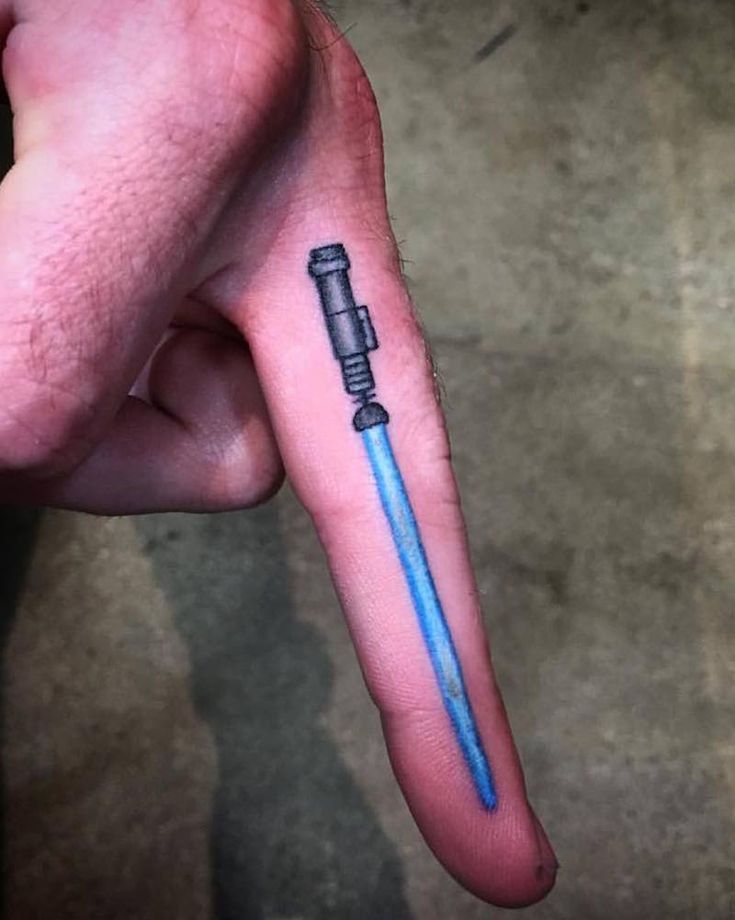 a person with a small tattoo on their left hand holding a blue and black pen